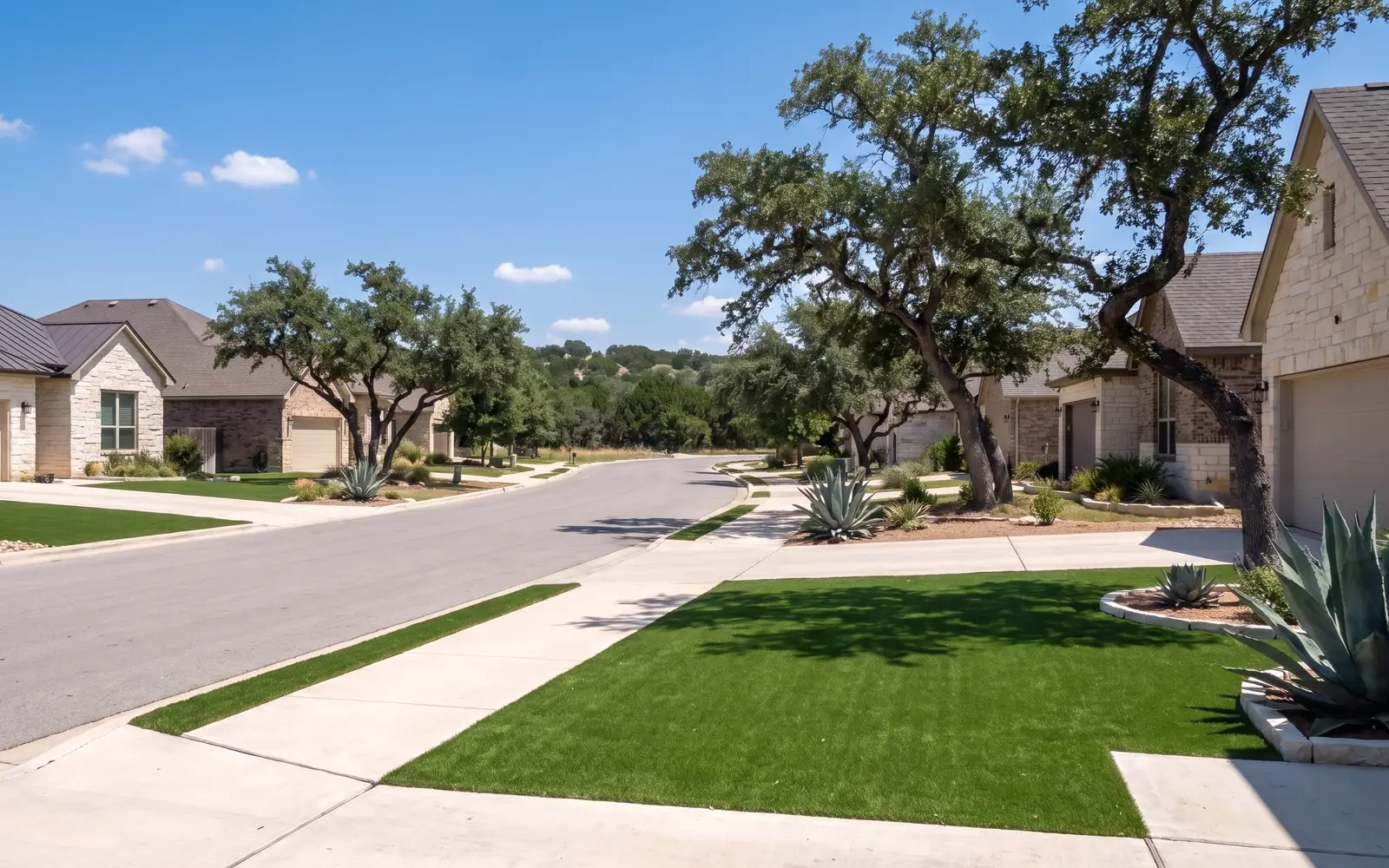 A suburban Austin street of limestone homes, some with turf front yards