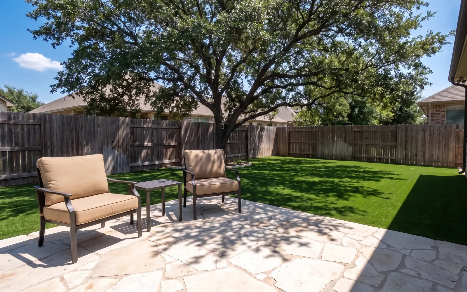 Artificial turf beside a stone patio in the shade of a live oak